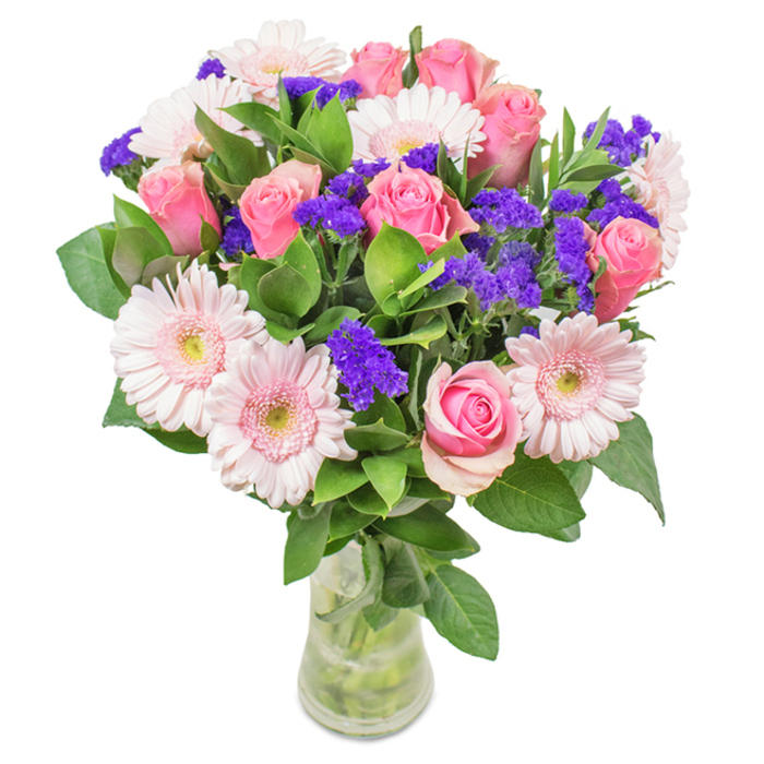Gleaming against a pure white background, this vibrant floral composition showcases Winchmore Hill's flair for graceful living. A carefully balanced centrepiece features seven to nine pastel pink roses, their petals spiralling in classic beauty as if capturing a fleeting London sunrise. Nestled among them are five to seven airy gerbera daisies with soft pink, almost pearly petals and luminous, pale centres. Rich clusters of vivid purple statice add striking contrast, bringing texture and depth echoed in Winchmore Hill's abundant local flora. Deep green foliage, fresh and luxuriant, forms an embracing foundation, reminiscent of the leafy avenues and private gardens that characterize this community. The arrangement's slender, transparent glass vase reveals the natural stems and pristine water within, creating a sense of purity and immediacy. Ideal as a dazzling gift for birthdays, anniversaries, or Mother's Day-or simply a charming accent for a Winchmore Hill office or home-this bouquet radiates celebration and affection, bridging traditional floristry with the unique local spirit of N21.